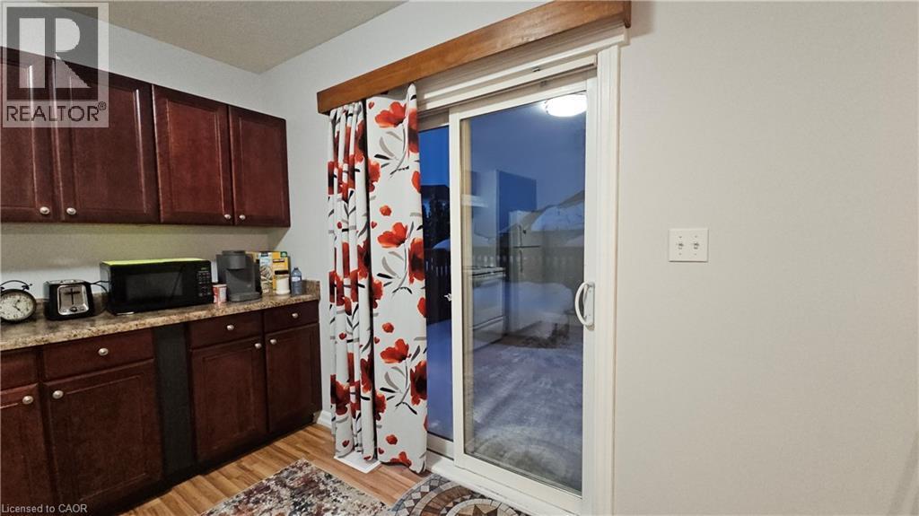 Kitchen featuring dark brown cabinetry, black microwave, light wood-style flooring, and light stone counters - 10 Doll Court Unit# Lower, Kitchener, ON - Indoor