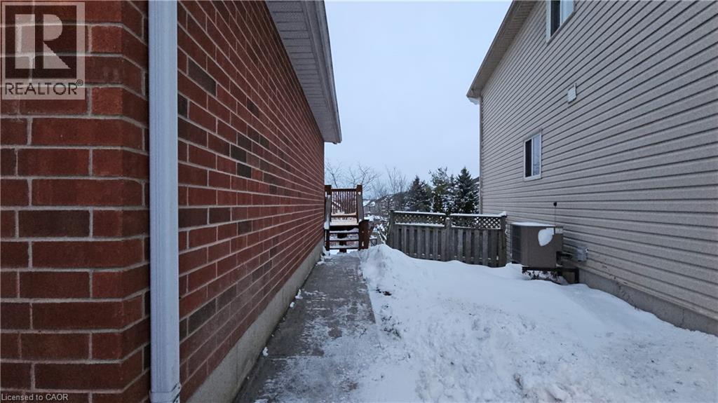 View of snow covered exterior with a wooden deck and brick siding - 10 Doll Court Unit# Lower, Kitchener, ON - Outdoor With Exterior