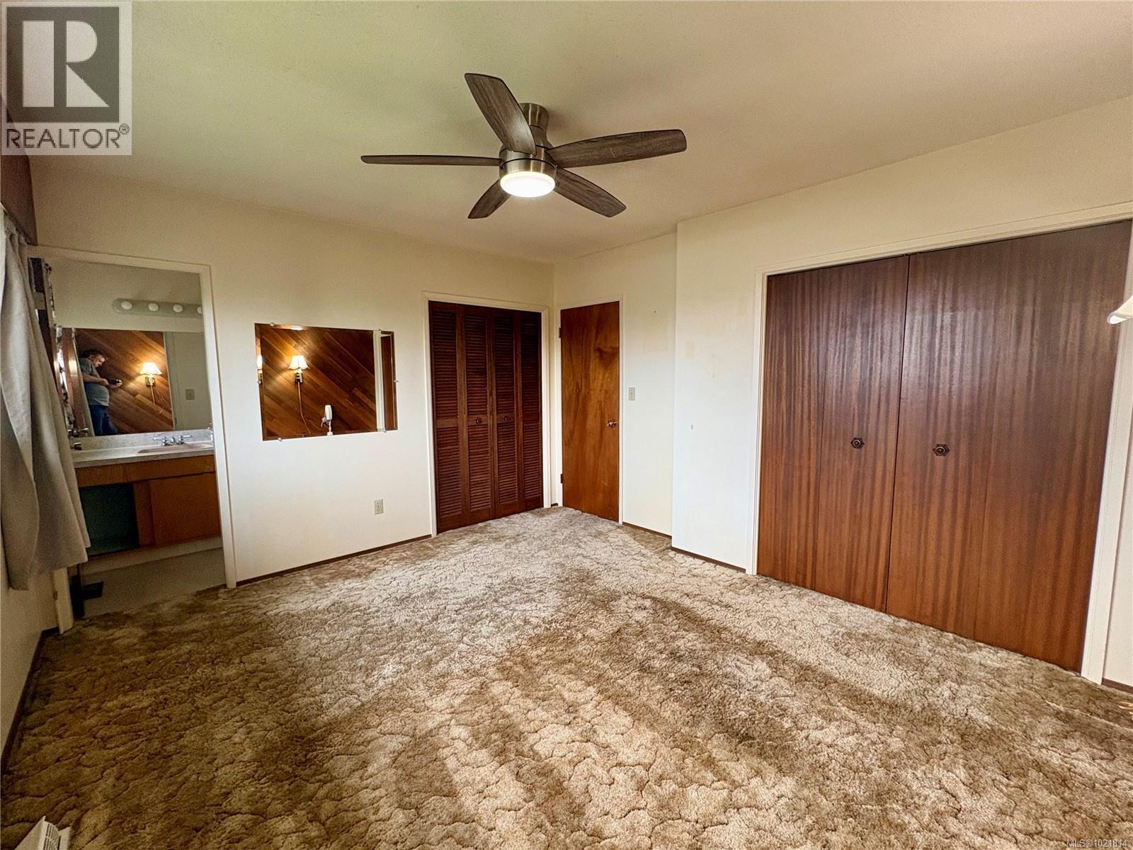 Unfurnished bedroom featuring two closets, connected bathroom, a ceiling fan, and carpet floors - 2738 14Th Ave, Port Alberni, BC - Indoor Photo Showing Other Room