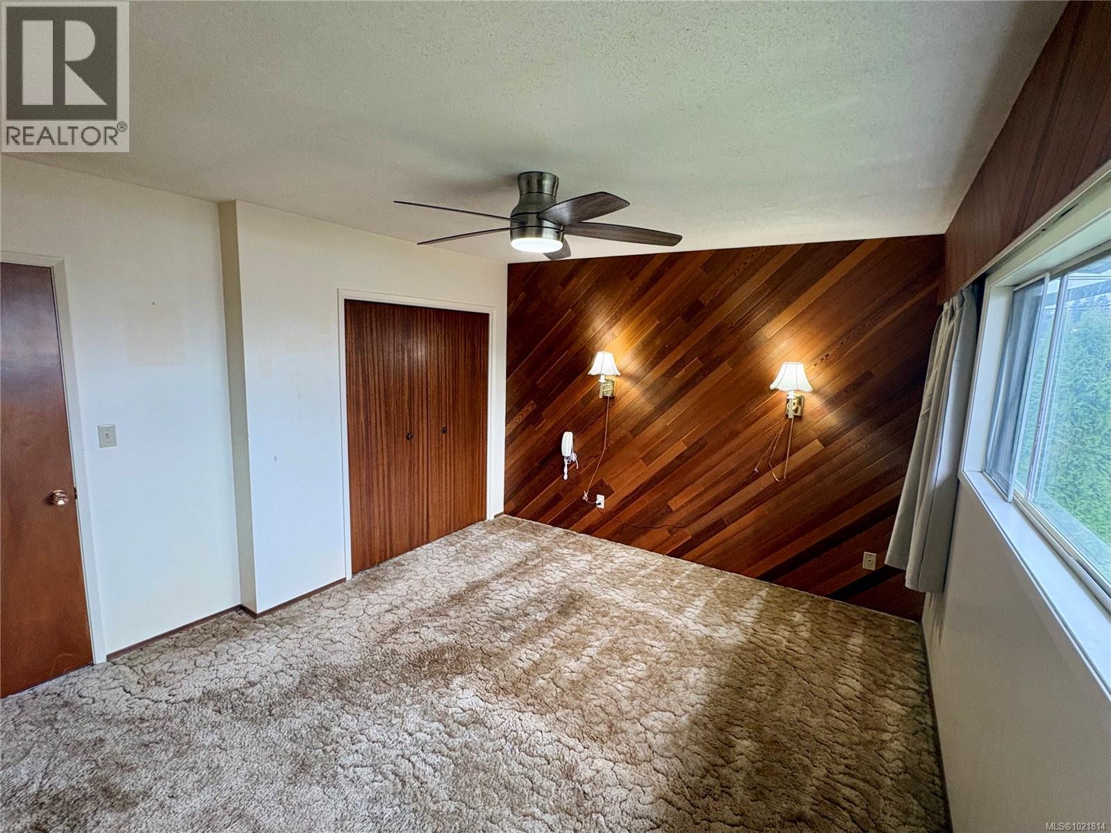 Unfurnished bedroom with wood walls, a closet, ceiling fan, a textured ceiling, and an accent wall - 2738 14Th Ave, Port Alberni, BC - Indoor