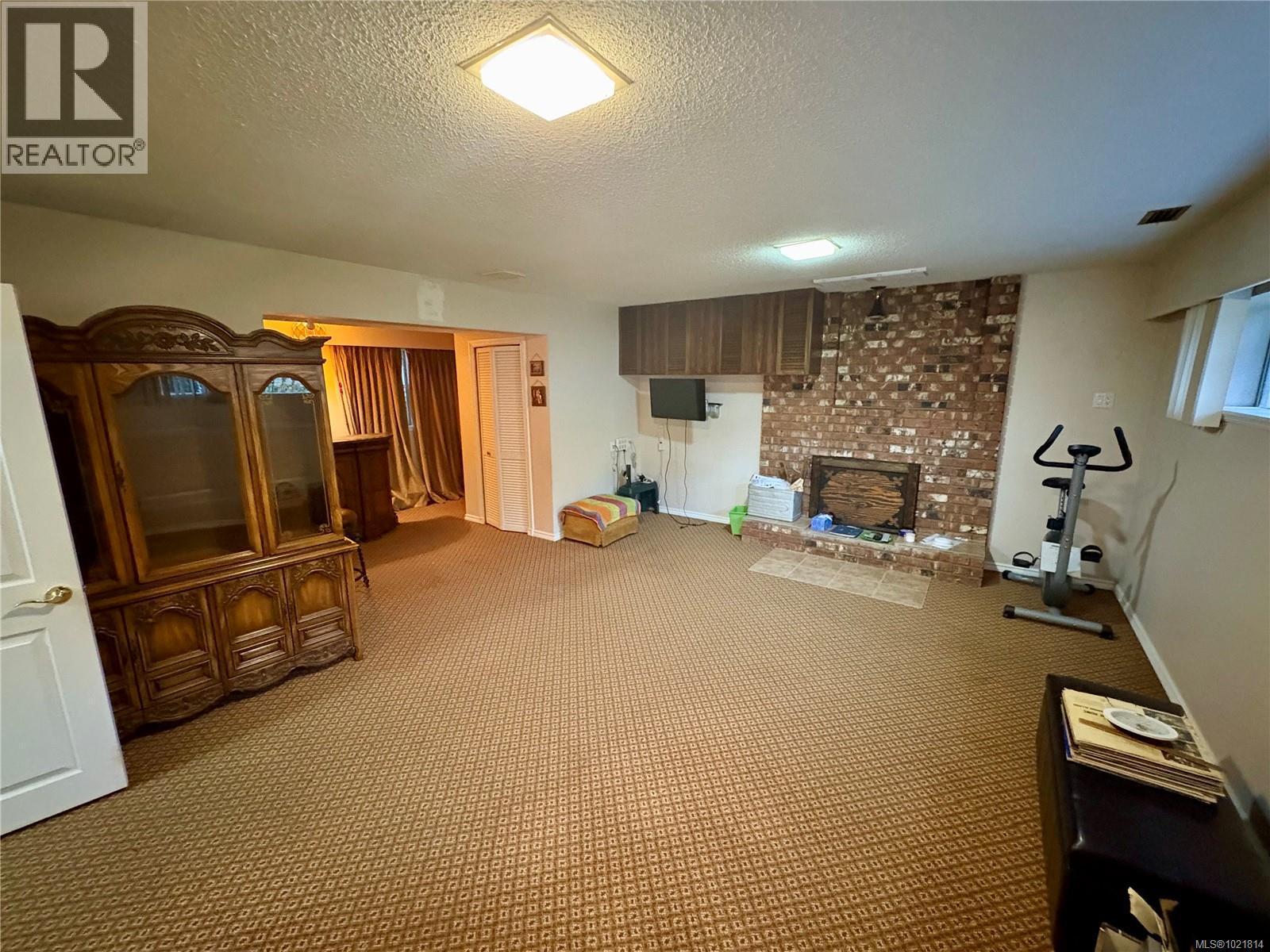 Exercise room featuring a textured ceiling and carpet floors - 2738 14Th Ave, Port Alberni, BC - Indoor Photo Showing Other Room With Fireplace