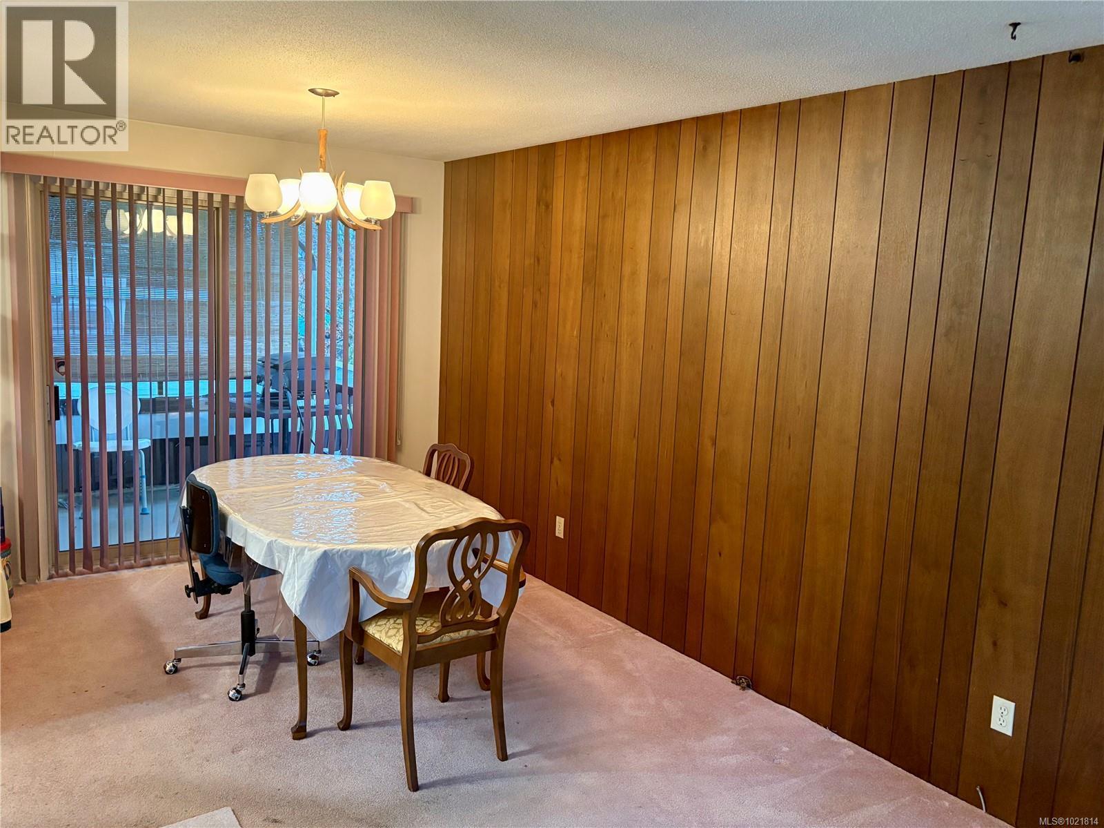 Carpeted dining area featuring wood walls, a chandelier, and a textured ceiling - 2738 14Th Ave, Port Alberni, BC - Indoor Photo Showing Dining Room