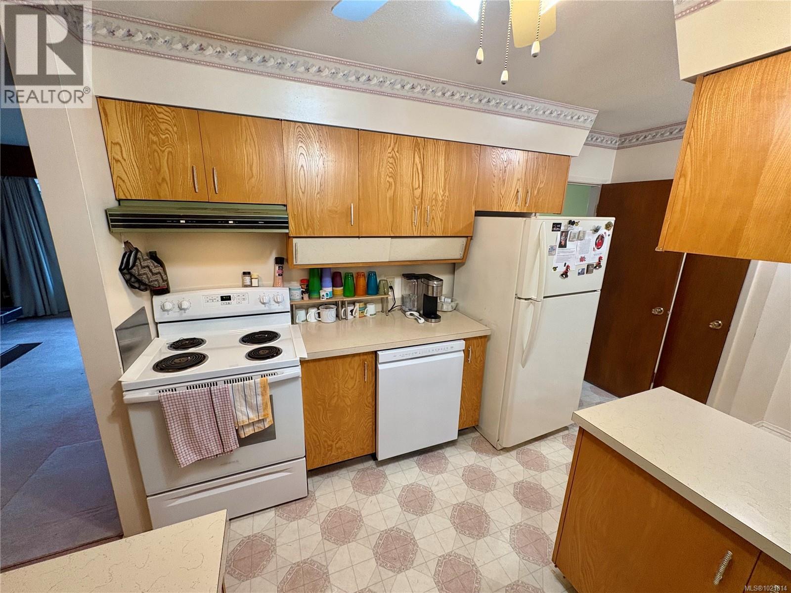 Kitchen featuring white appliances, light floors, brown cabinets, light countertops, and ventilation hood - 2738 14Th Ave, Port Alberni, BC - Indoor Photo Showing Kitchen