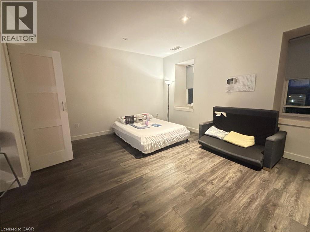 Bedroom featuring dark wood-type flooring and baseboards - 25 Main Street Unit# 302, Cambridge, ON - Indoor