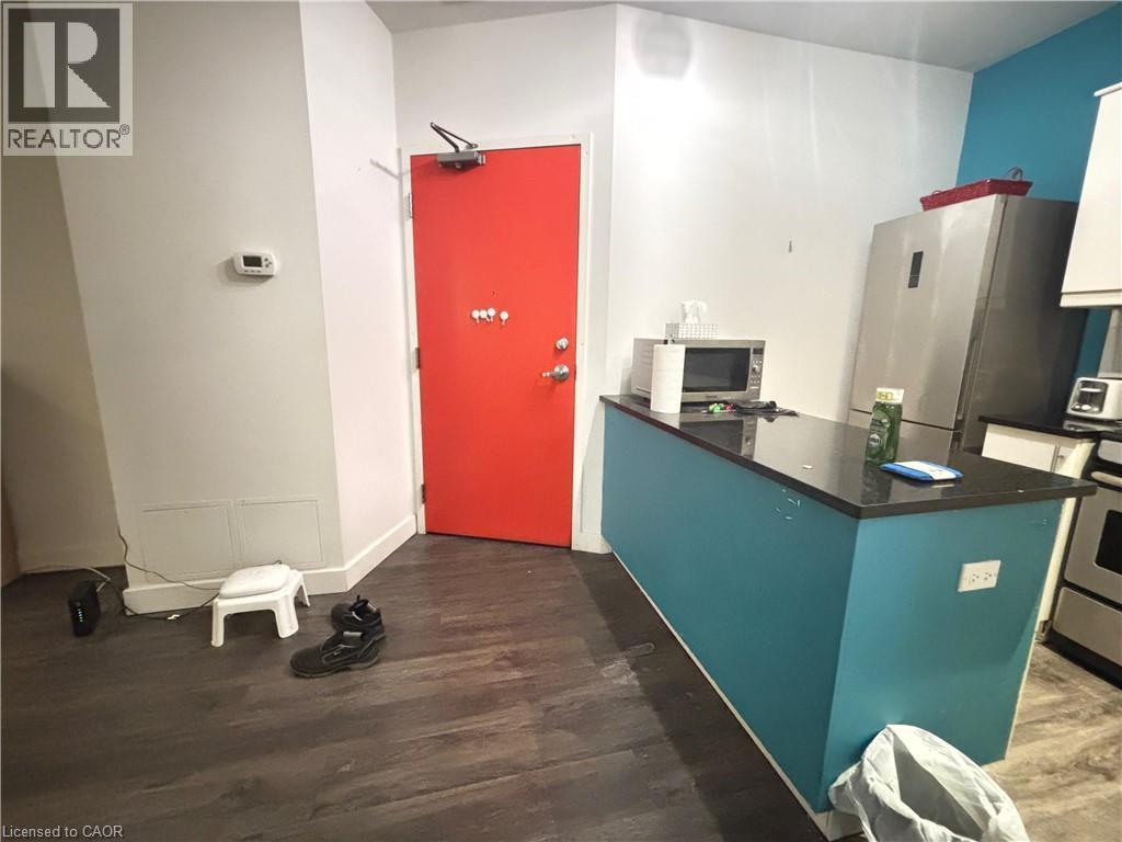 Kitchen featuring a peninsula, stainless steel appliances, dark wood finished floors, dark stone counters, and white cabinetry - 25 Main Street Unit# 302, Cambridge, ON - Indoor