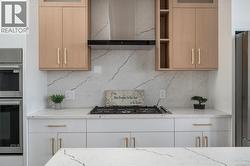 Kitchen with backsplash, wall chimney range hood, stainless steel appliances, and light stone counters -