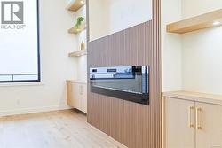 Kitchen with open shelves, light wood-type flooring, light countertops, and light brown cabinets -