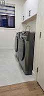 Laundry room with cabinet space, washer and clothes dryer, and light wood-style floors -