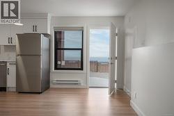 Kitchen featuring appliances with stainless steel finishes, white cabinets, light wood-style flooring, and baseboard heating -