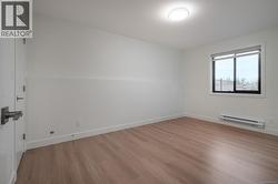 Empty room with light wood-style flooring and baseboard heating -