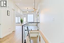 Hall with light wood finished floors, a chandelier, and recessed lighting -