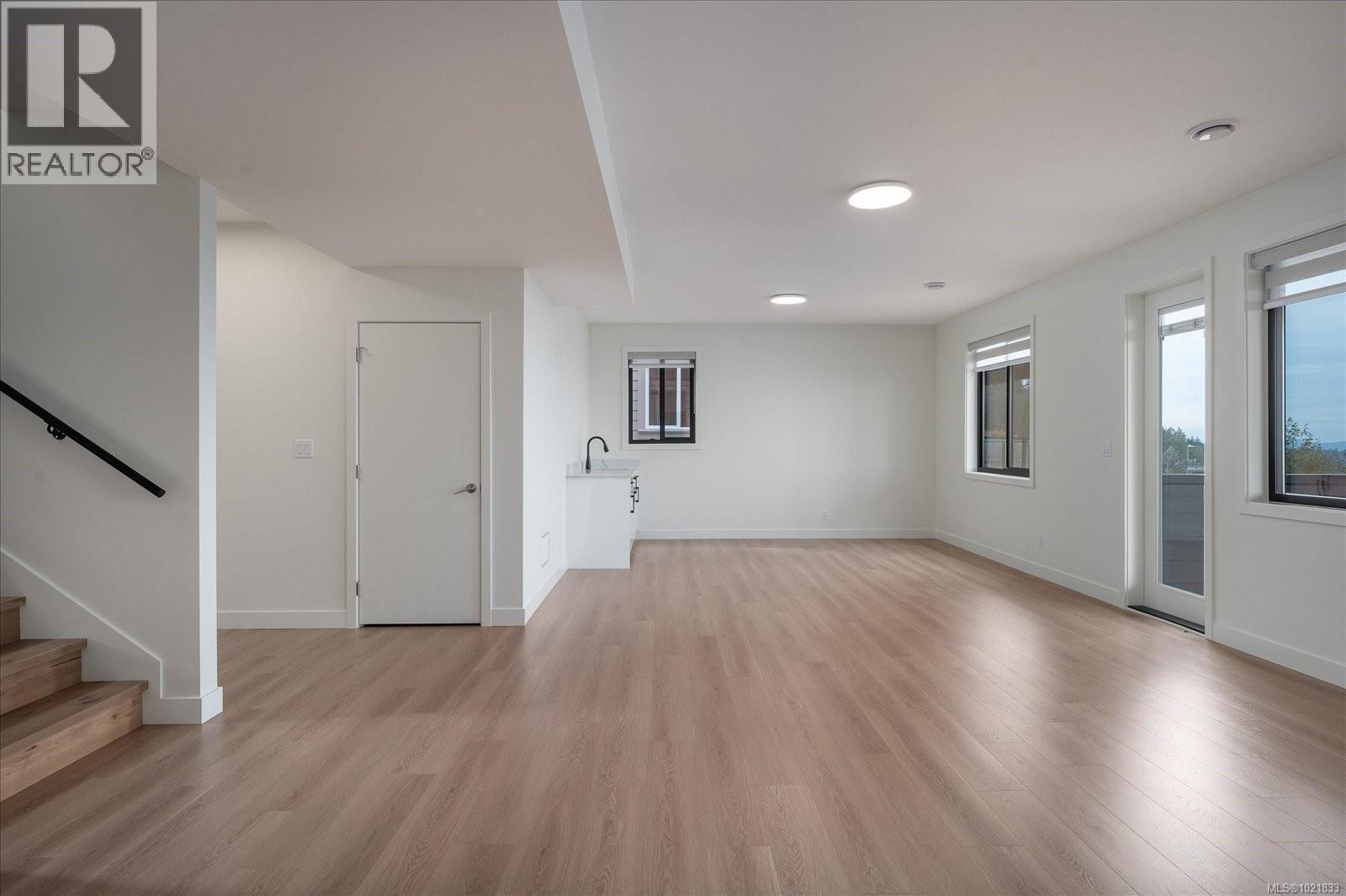 Unfurnished living room featuring light wood-type flooring and stairway - 4680 Ambience Dr, Nanaimo, BC - Indoor Photo Showing Other Room