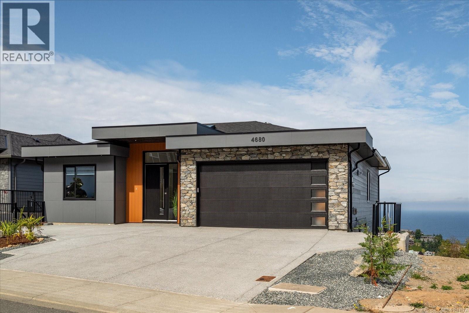 Modern home featuring stone siding, driveway, and an attached garage - 4680 Ambience Dr, Nanaimo, BC - Outdoor