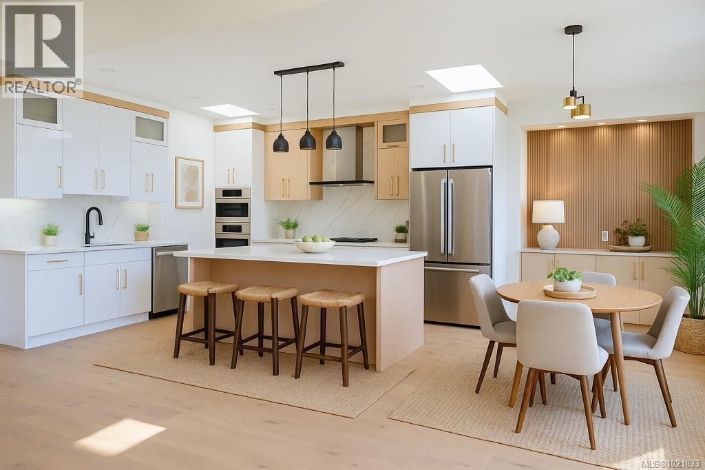 Kitchen with glass insert cabinets, hanging light fixtures, stainless steel appliances, and wall chimney range hood - 4680 Ambience Dr, Nanaimo, BC - Indoor