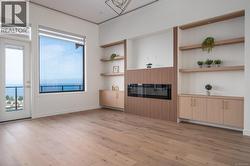 Unfurnished living room featuring ornamental molding, light wood-type flooring, and built in shelves -