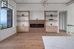 Unfurnished living room featuring light wood-style flooring, ornamental molding, and built in shelves -