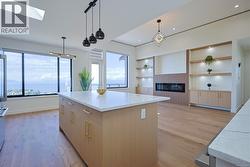 Kitchen featuring light stone countertops, light wood-type flooring, pendant lighting, a center island, and a skylight -