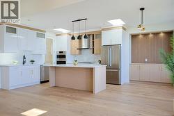 Kitchen featuring pendant lighting, appliances with stainless steel finishes, white cabinets, and wall chimney exhaust hood -