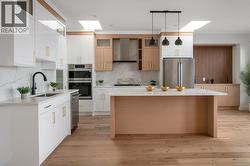 Kitchen featuring a skylight, pendant lighting, tasteful backsplash, and light stone counters -