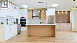Kitchen with hanging light fixtures, a skylight, white cabinets, stainless steel appliances, and recessed lighting -
