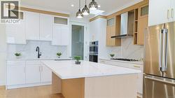 Kitchen with appliances with stainless steel finishes, wall chimney exhaust hood, a center island, light stone countertops, and decorative light fixtures -