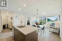 Kitchen featuring light wood-style flooring, dark brown cabinetry, hanging light fixtures, modern cabinets, and open floor plan -