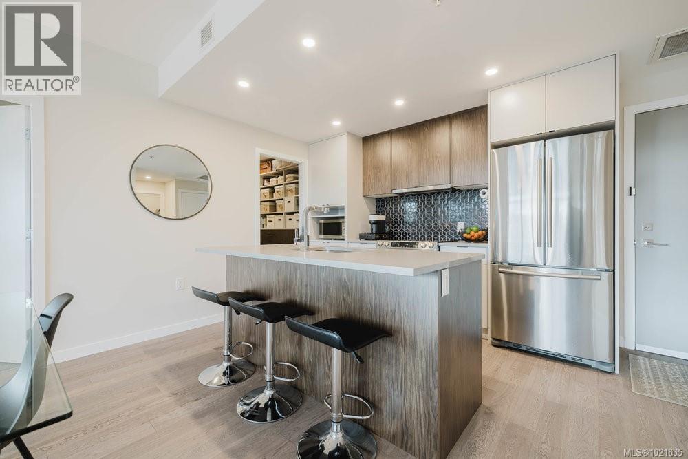 Kitchen featuring stainless steel appliances, quartz countertops, a kitchen island with sink, modern cabinets, and light wood-style floors - 210 881 Short St, Saanich, BC - Indoor Photo Showing Kitchen With Stainless Steel Kitchen With Upgraded Kitchen