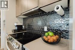 Kitchen featuring stainless steel range with electric stovetop, exhaust hood, and light stone countertops -