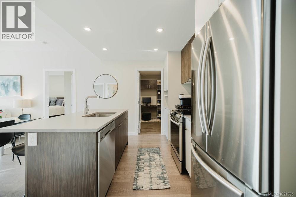 Kitchen featuring appliances with stainless steel finishes, recessed lighting, a center island with sink, light wood-style flooring, and modern cabinets - 210 881 Short St, Saanich, BC - Indoor Photo Showing Kitchen With Stainless Steel Kitchen With Upgraded Kitchen