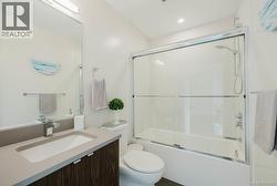 Bathroom featuring vanity and bath / shower combo with glass door -