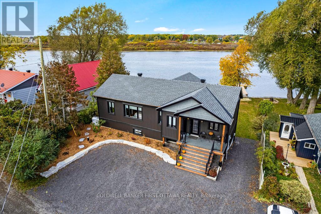 Summer view of the bungalow with curb appeal - 38 Tuttle Point Road, Edwardsburgh/Cardinal, ON - Outdoor With Body Of Water