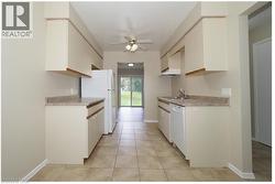 Kitchen featuring light countertops, light tile patterned floors, and white appliances -
