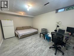 Bedroom with freestanding refrigerator, a desk, and a textured ceiling -