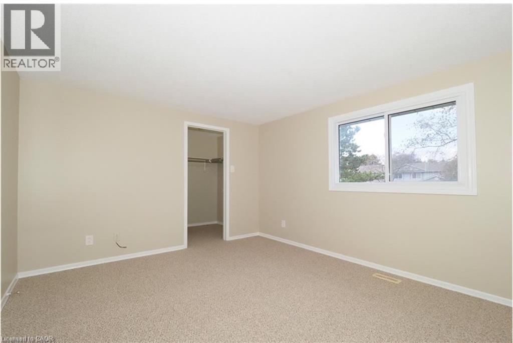 Unfurnished bedroom with a spacious closet and light carpet - 455 Kingscourt Drive Unit# 3, Waterloo, ON - Indoor Photo Showing Other Room
