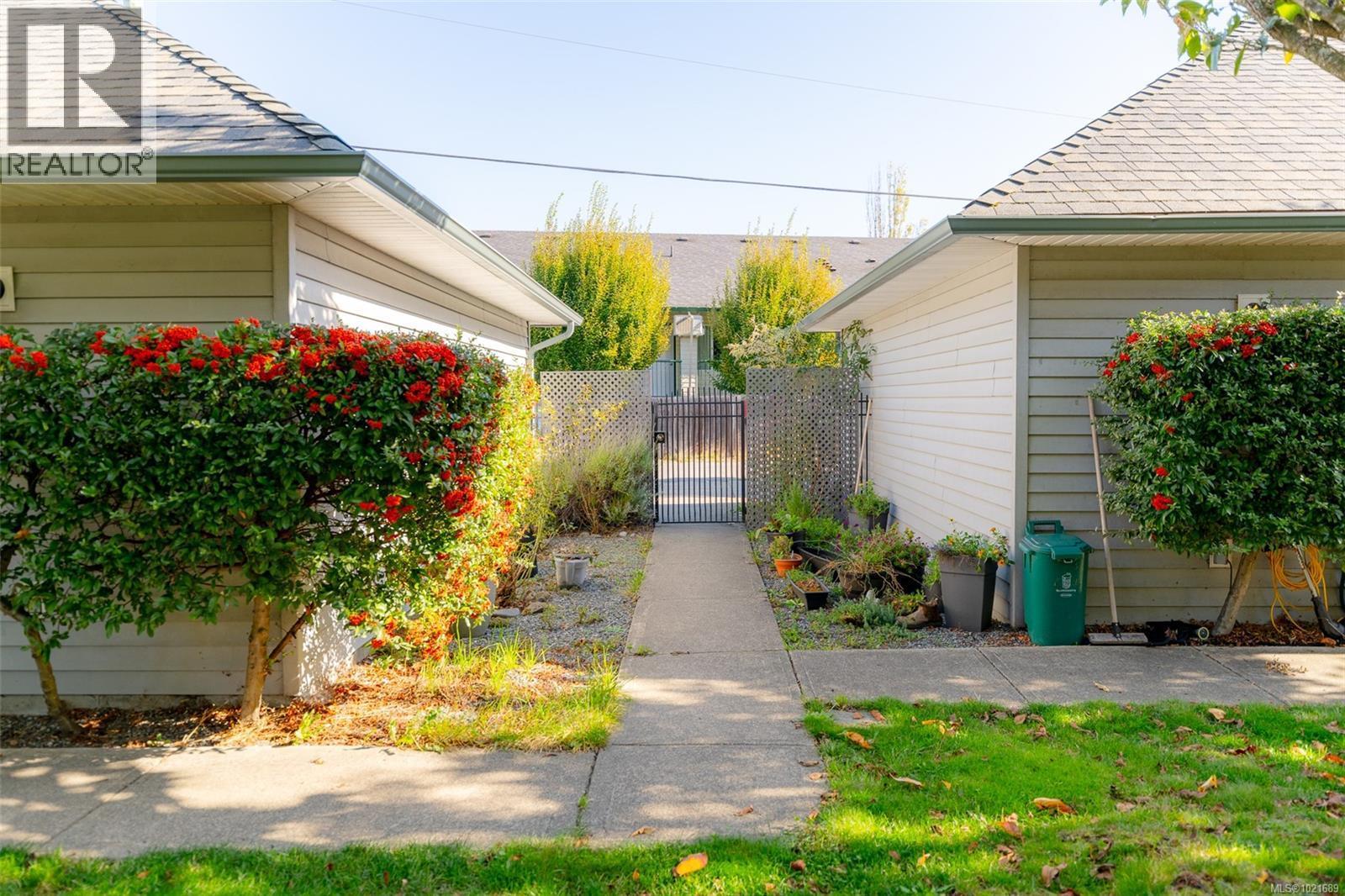 View of property exterior with a gate and a shingled roof - 101 211 Victoria Rd, Nanaimo, BC
