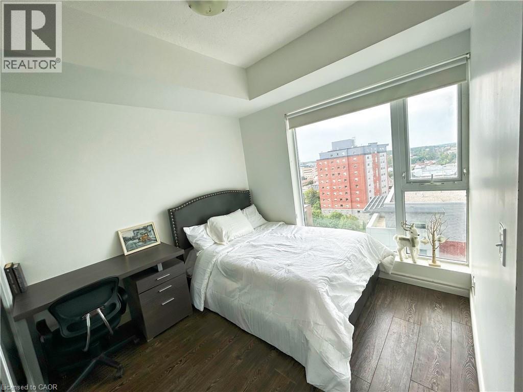 Bedroom with dark wood-style flooring, a view of city, and a desk - 158 King Street N Unit# 1504, Waterloo, ON - Indoor Photo Showing Bedroom