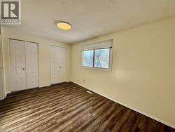 Unfurnished bedroom featuring a textured ceiling, multiple closets, and dark wood-style floors -