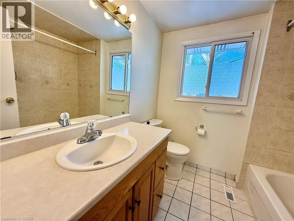 Full bath featuring vanity, light tile patterned floors, healthy amount of natural light, and bathing tub / shower combination - 79 Lillian Drive Unit# A, Waterloo, ON - Indoor Photo Showing Bathroom