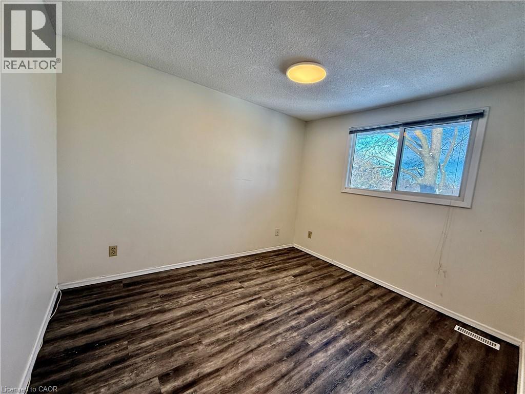 Empty room featuring a textured ceiling and dark wood finished floors - 79 Lillian Drive Unit# A, Waterloo, ON - Indoor Photo Showing Other Room