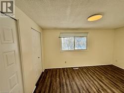 Unfurnished bedroom featuring a textured ceiling, dark wood-type flooring, and a closet -