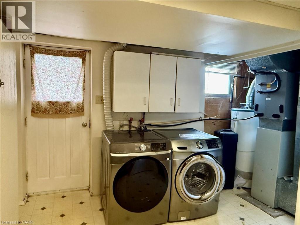 Laundry room featuring cabinet space, heating unit, light flooring, separate washer and dryer, and water heater - 79 Lillian Drive Unit# A, Waterloo, ON - Indoor Photo Showing Laundry Room