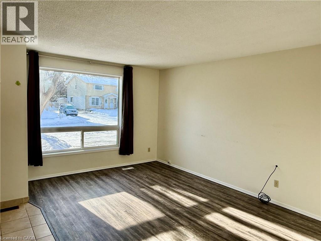 Empty room featuring a textured ceiling and wood finished floors - 79 Lillian Drive Unit# A, Waterloo, ON - Indoor Photo Showing Other Room