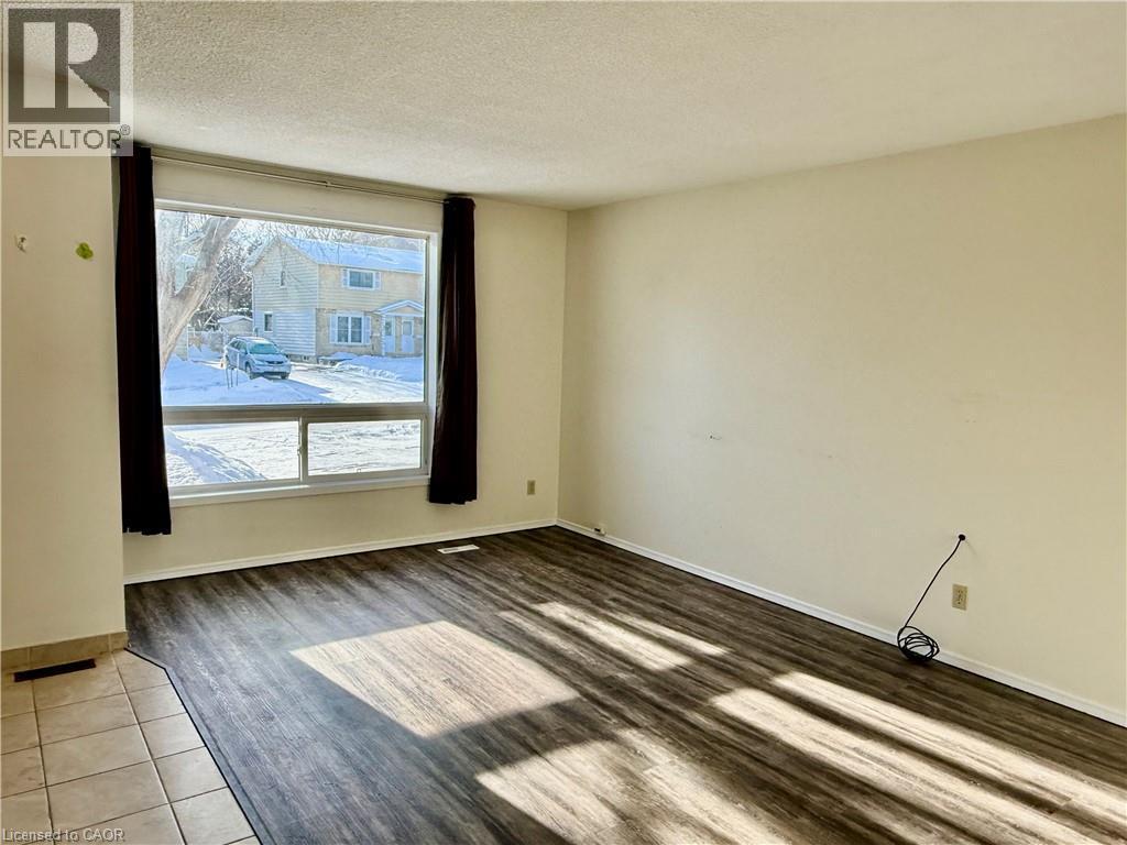 Empty room with a textured ceiling and wood finished floors - 79 Lillian Drive Unit# A, Waterloo, ON - Indoor Photo Showing Other Room