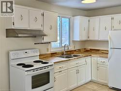 Kitchen with white appliances, white cabinetry, under cabinet range hood, and light tile patterned floors -