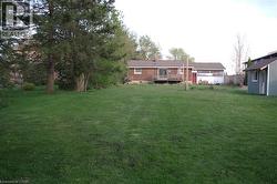 View of grassy yard with a wooden deck and a storage unit -