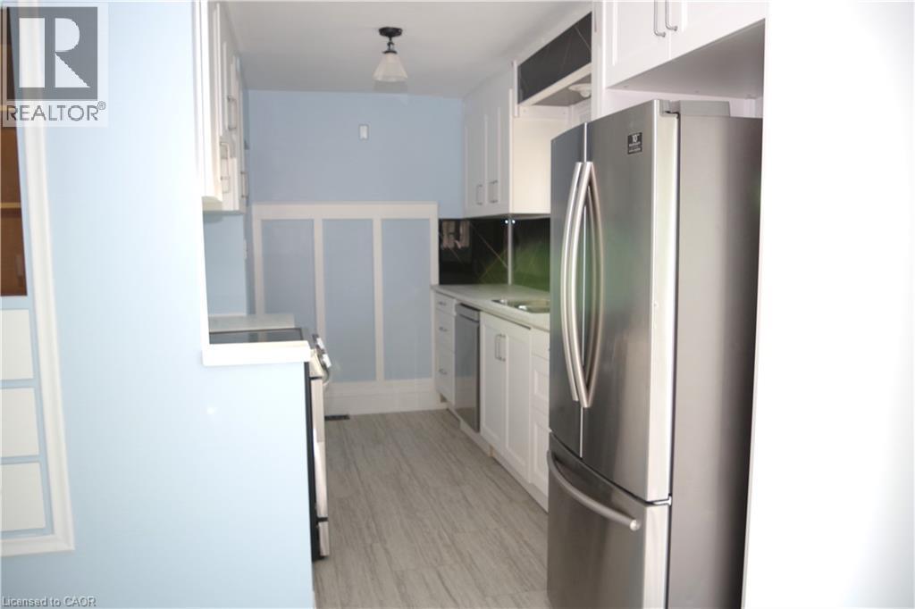 Kitchen featuring white cabinetry, stainless steel appliances, and light countertops - 425 Wellington Street E, Mount Forest, ON - Indoor Photo Showing Other Room