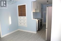 Kitchen with white cabinets, light countertops, appliances with stainless steel finishes, wood tiled floors, and decorative light fixtures -