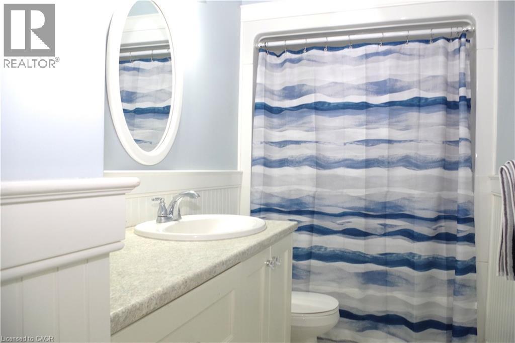 Bathroom with wainscoting, vanity, curtained shower, and a decorative wall - 425 Wellington Street E, Mount Forest, ON - Indoor Photo Showing Bathroom