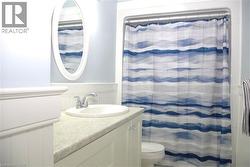 Bathroom with wainscoting, vanity, curtained shower, and a decorative wall -