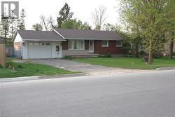 Ranch-style house with a front yard, a garage, asphalt driveway, a chimney, and roof with shingles -